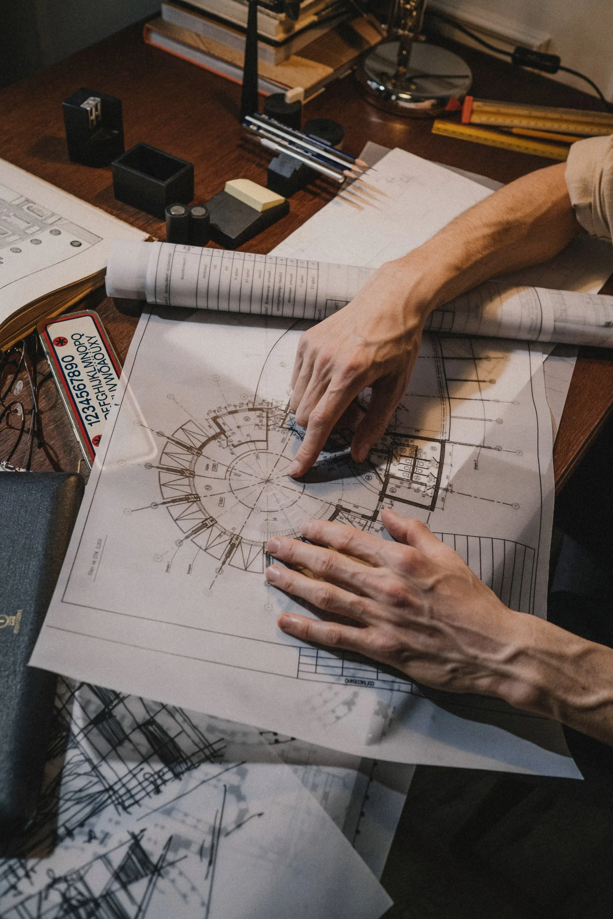 Mãos de arquiteto desenhando uma planta sobre a mesa de trabalho